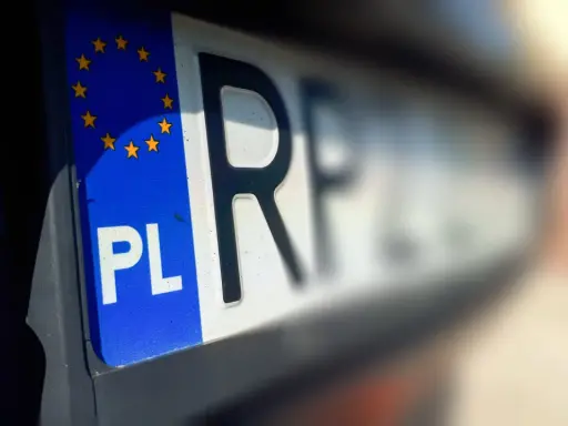 Zbliżenie na tablice rejestracyjne województwa z symbolem PL i gwiazdkami UE.