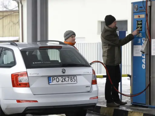 Srebrny samochód Skoda z podłączoną dyszą do tankowania gazu CNG na stacji.