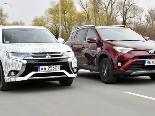 Dwa SUV-y, biały Mitsubishi Outlander i czerwony Toyota RAV4, jadące po drodze. Idealne dla szukających najmniej awaryjne SUV-y 10 letnie.