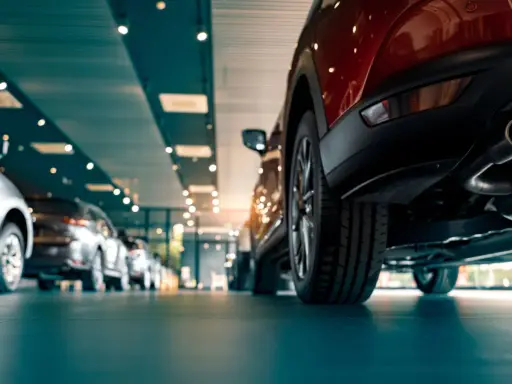 Nowe samochody w salonie, w tym czerwony SUV z widocznym układem wydechowym. Zastanawiasz się, ac co to za model?