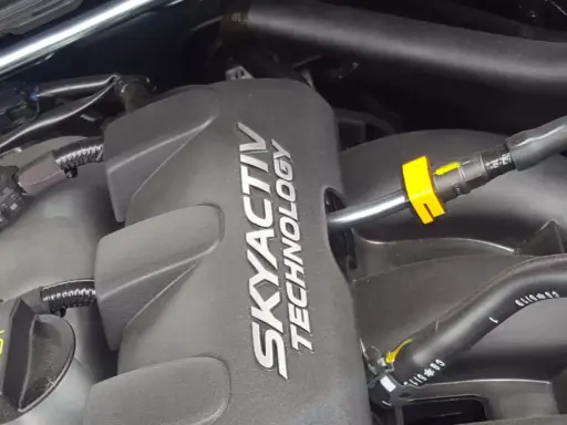 Silnik SKYACTIV TECHNOLOGY, jeden z najlepszych silników benzynowych, z widocznymi przewodami i złączkami.