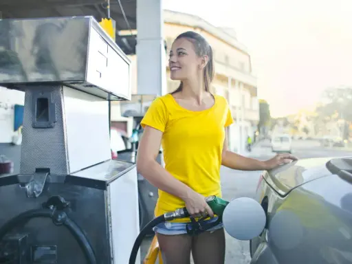 Uśmiechnięta dziewczyna tankuje auto, nalewając Vervę 98.