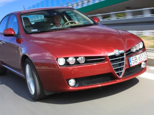 Czerwone Alfa Romeo 159 1.9 JTD pędzi po autostradzie.