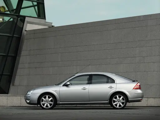 Srebrny Ford Mondeo MK3 2.0 TDCI stoi przed nowoczesnym budynkiem z kamienną fasadą.