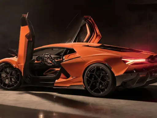 Pomarańczowy Lamborghini Revuelto z otwartymi drzwiami typu nożycowego, prezentujący sportowe wnętrze i agresywną sylwetkę.