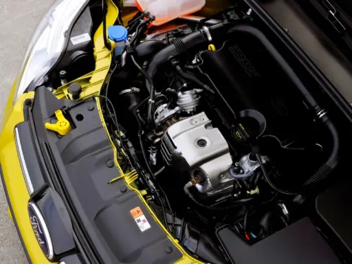 Silnik 1.0 Ecoboost w żółtym Fordzie. Widoczne elementy układu dolotowego, turbosprężarki i osłony silnika.