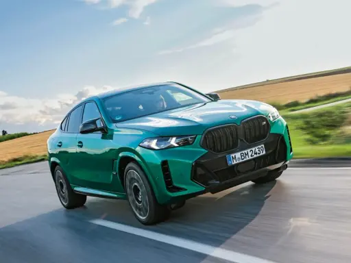 Zielony BMW X6 M Competition, jakby wyłaniał się z krajobrazu, niczym **formentor** w drodze na szczyt.
