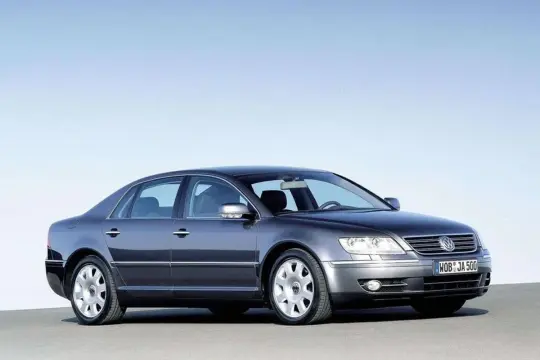 Elegancki, ciemnoszary VW Phaeton W12 z charakterystycznymi felgami, prezentujący się na tle błękitnego nieba.