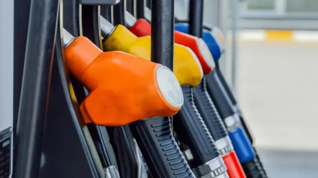 Kolorowe pistolety na stacji paliw, gotowe do tankowania. Jeden z nich, pomarańczowy, sugeruje, że można nim nalać verva diesel.