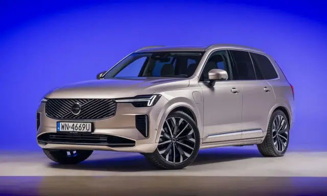 Eleganckie, nowe Volvo w kolorze szampańskim prezentuje się imponująco na tle niebieskiego tła.