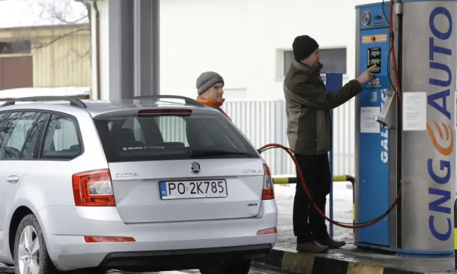 Srebrny samochód Skoda z podłączoną dyszą do tankowania gazu CNG na stacji.