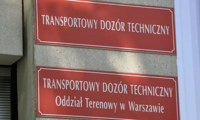 Dwa czerwone szyldy z białym napisem "TRANSPORTOWY DOZÓR TECHNICZNY". Dolny szyld zawiera dodatkowo "Oddział Terenowy w Warszawie". Miejsce, gdzie można uzyskać homologację.