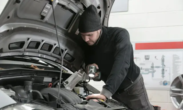 Mechanik z latarką bada silnik 1.6 TDI.