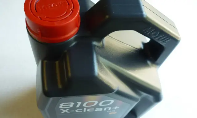 Czarny kanister z olejem silnikowym Motul 8100 X-clean+ z czerwoną zakrętką.
