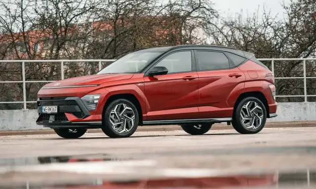 Nowy Hyundai Kona Hybrid w kolorze ognistej czerwieni, z czarnym dachem, prezentuje się dynamicznie na tle zimy.