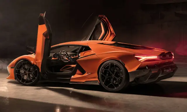 Pomarańczowy Lamborghini Revuelto z otwartymi drzwiami typu nożycowego, prezentujący sportowe wnętrze i agresywną sylwetkę.