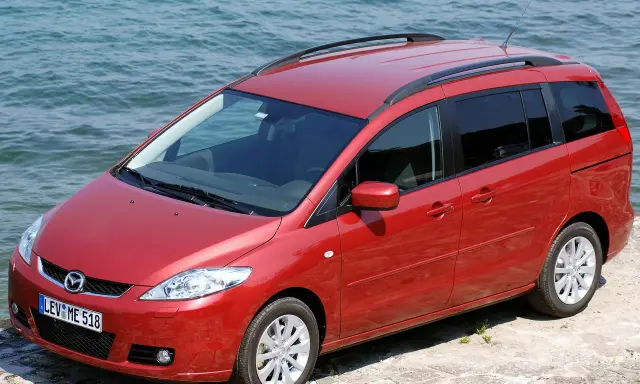 Czerwona Mazda 5 2.0 benzyna zaparkowana przy wodzie.