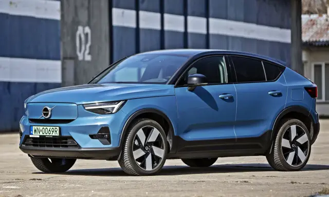 Niebieskie Volvo C40 Recharge, elektryczny SUV, parkuje przed budynkiem z numerem 02.