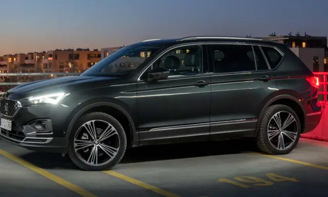 Ciemnozielony SUV, jeden z najbardziej polecanych samochodów 7-osobowych, zaparkowany na dachu parkingu nocą.