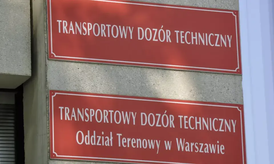 Dwa czerwone szyldy z białym napisem "TRANSPORTOWY DOZÓR TECHNICZNY". Dolny szyld zawiera dodatkowo "Oddział Terenowy w Warszawie". Miejsce, gdzie można uzyskać homologację.