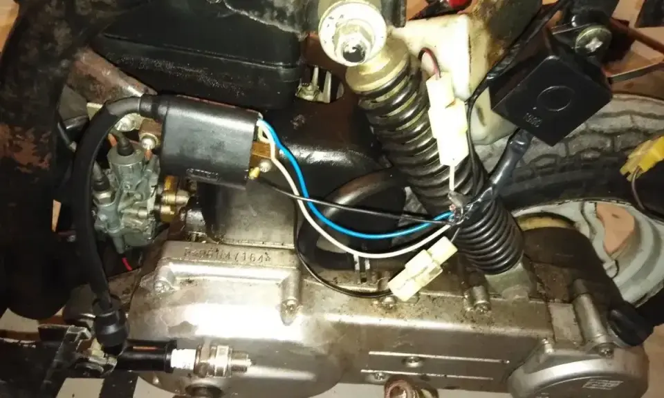 Silnik motoroweru z widocznym iskrownikiem, gaźnikiem i świecą zapłonową.