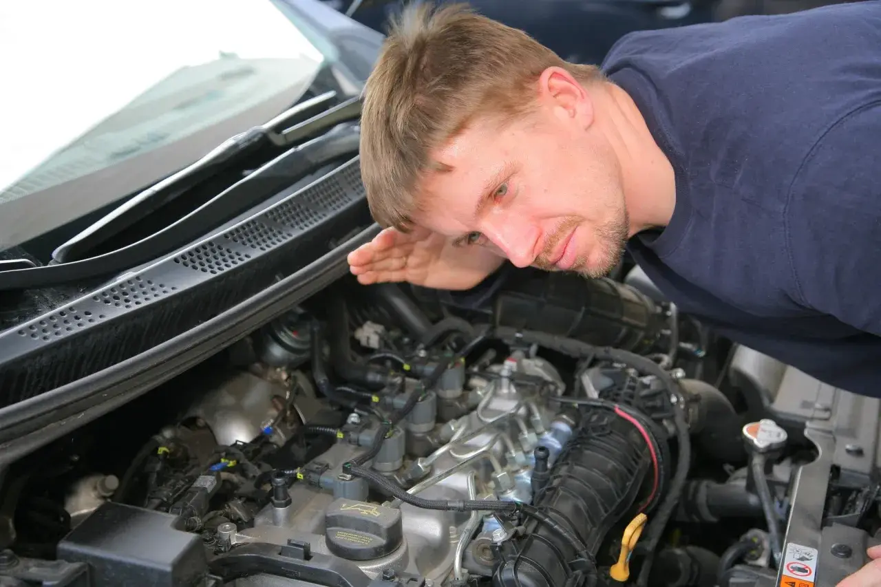 Mechanik nasłuchuje silnika, szukając oznak nieszczelnej odmy.