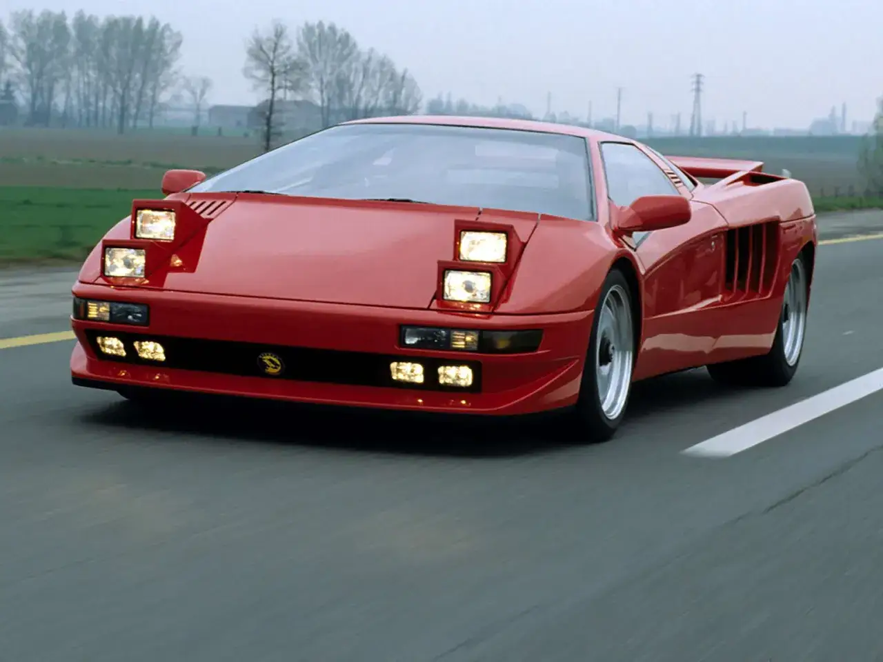 Czerwony Lamborghini Diablo z podnoszonymi światłami jedzie po drodze.