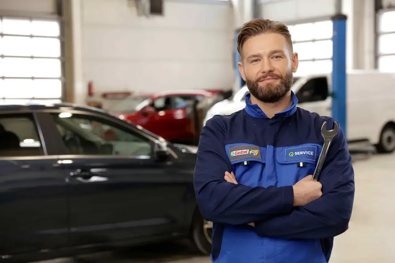 Uśmiechnięty mechanik z kluczem w ręku, gotowy do pracy. Jego profesjonalizm budzi zaufanie, a pozytywna opinia o jego usługach jest zasłużona.