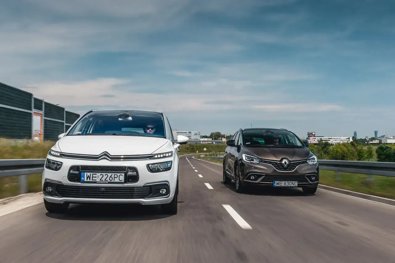 Biały Citroen Picasso i brązowy minivan jadą drogą.