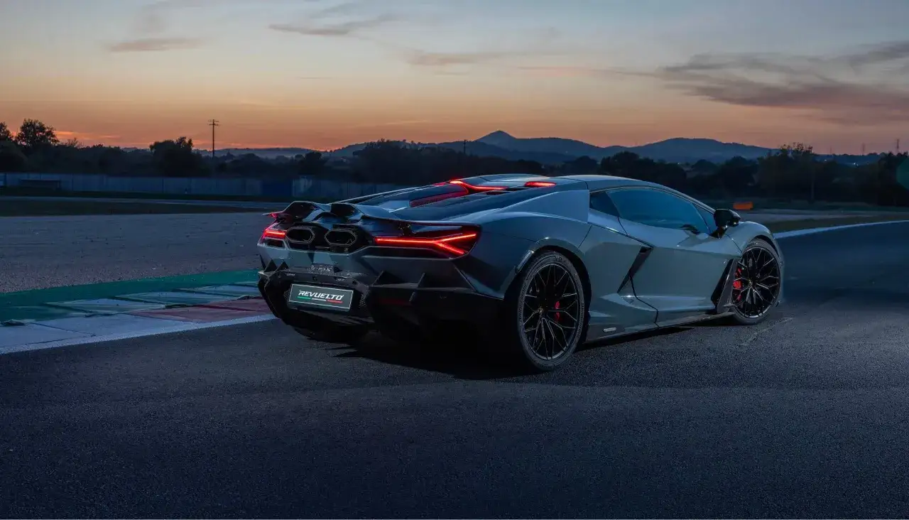 Szary Lamborghini Revuelto na torze wyścigowym o zachodzie słońca.