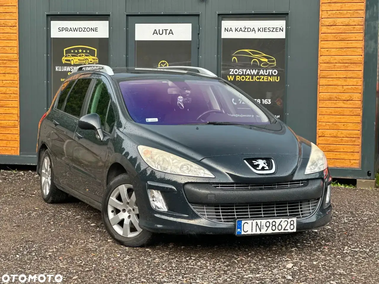 Ciemnozielony Peugeot 308 2008, kombi, stoi przed budynkiem z napisami 