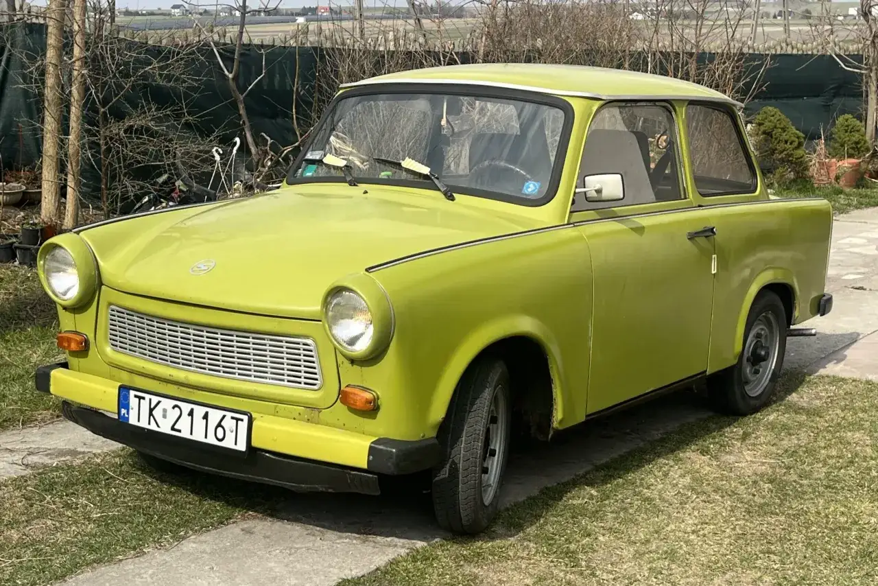 Zielony trabant z polskimi tablicami rejestracyjnymi TK 2116T stoi na trawniku.