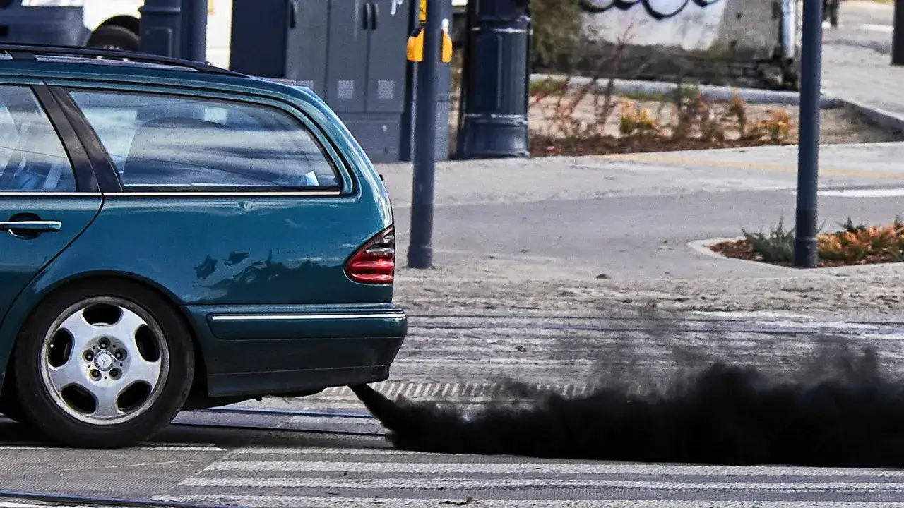 Zielony kombi na pasach dla pieszych. Z rury wydechowej wydobywa się gęsty, czarny dym – to znak, że diesel kopci na czarno.
