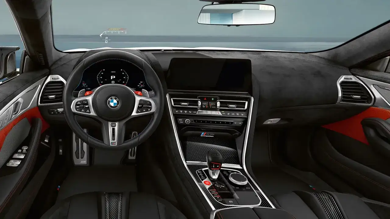 Wnętrze BMW M850i z cyfrowym kokpitem, sportową kierownicą i efektownymi czerwonymi akcentami.