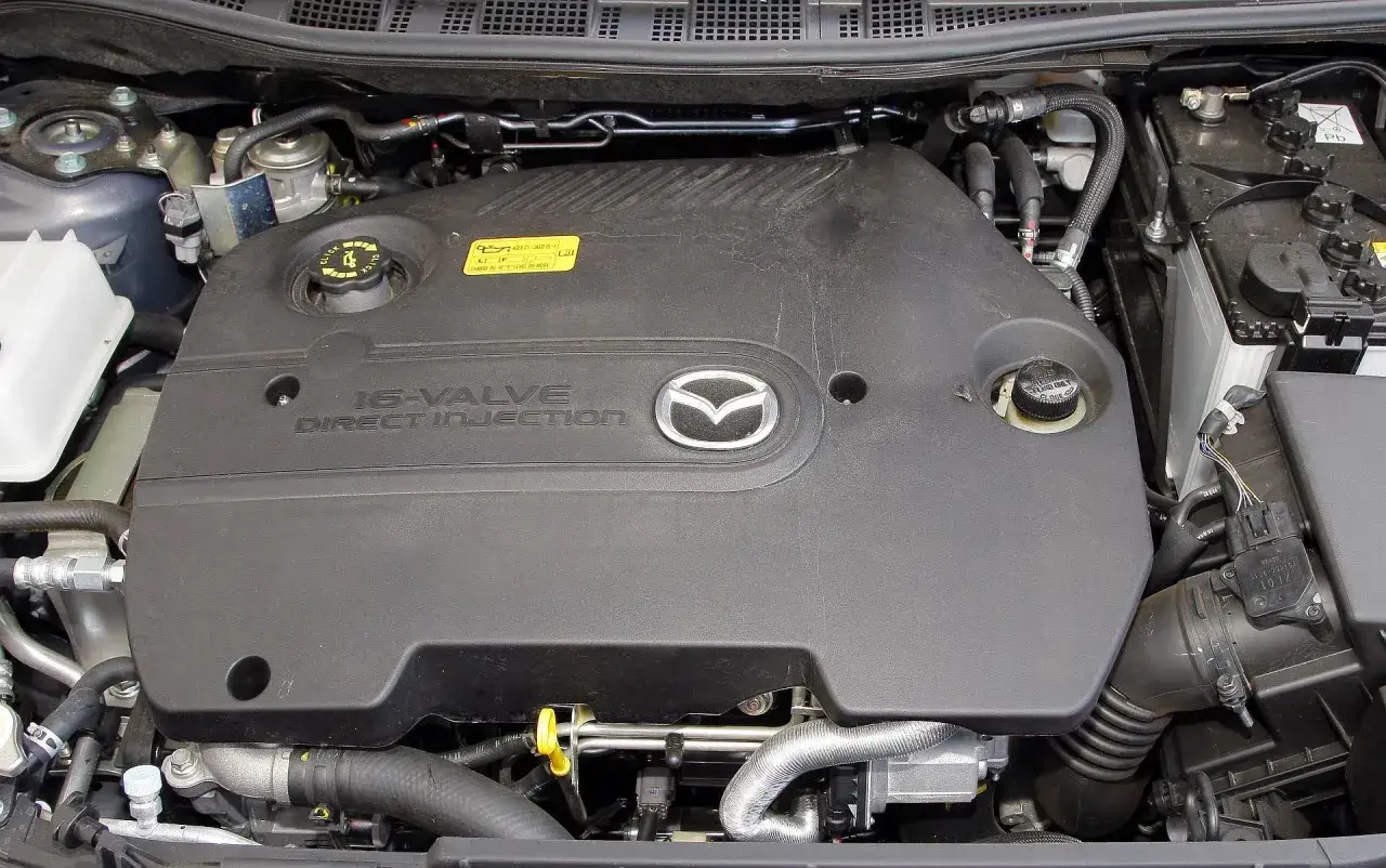 Silnik Mazda 5 2.0 benzyna. Widoczny czarny plastikowy dekiel z logo Mazdy i napisem