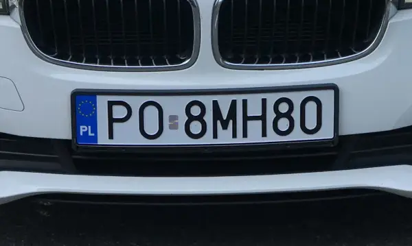 Tablice rejestracyjne sprawdzanie: polskie PO-8MH80 na białym samochodzie.