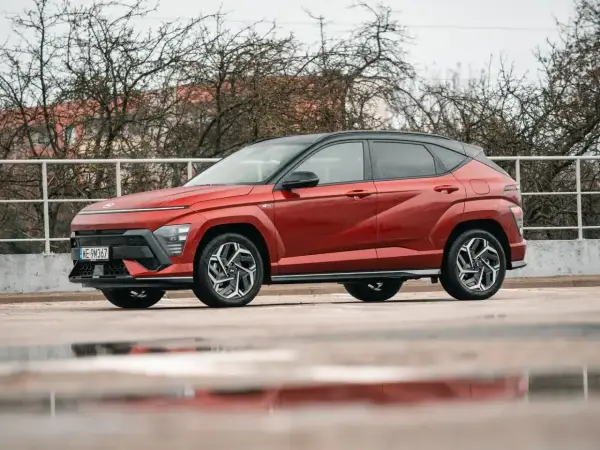 Nowy Hyundai Kona Hybrid w kolorze ognistej czerwieni, z czarnym dachem, prezentuje się dynamicznie na tle zimy.