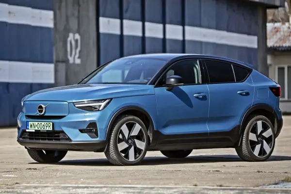 Niebieskie Volvo C40 Recharge, elektryczny SUV, parkuje przed budynkiem z numerem 02.