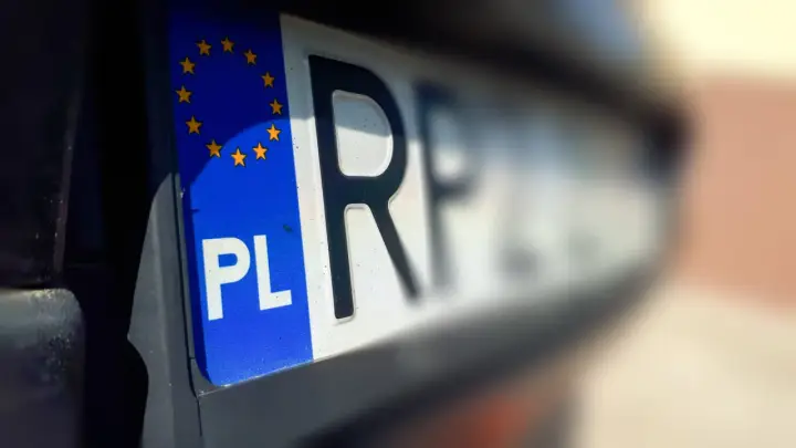 Zbliżenie na tablice rejestracyjne województwa z symbolem PL i gwiazdkami UE.
