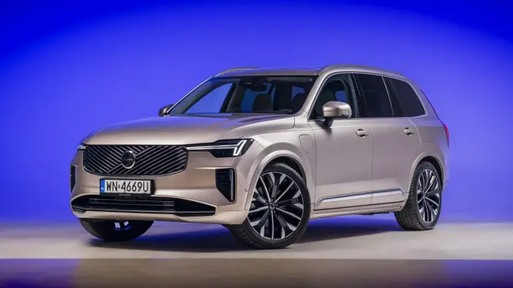Eleganckie, nowe Volvo w kolorze szampańskim prezentuje się imponująco na tle niebieskiego tła.