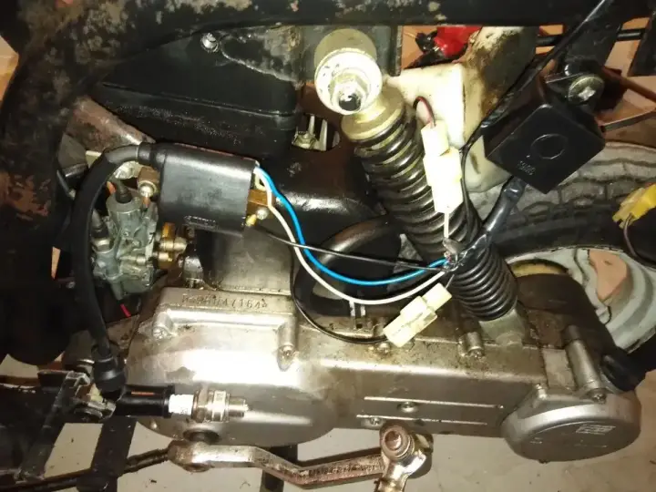 Silnik motoroweru z widocznym iskrownikiem, gaźnikiem i świecą zapłonową.