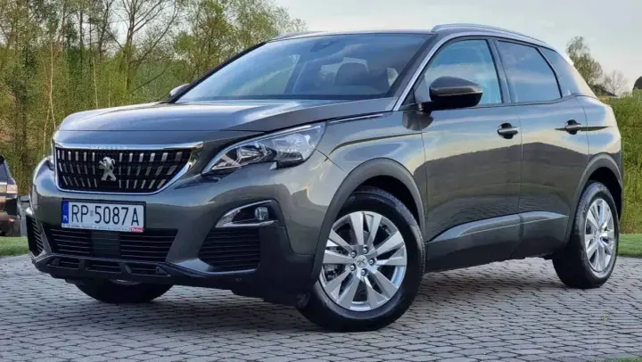 Szary Peugeot 3008 używany z salonu, z polskimi tablicami RP 5087A, zaparkowany na kostce brukowej.