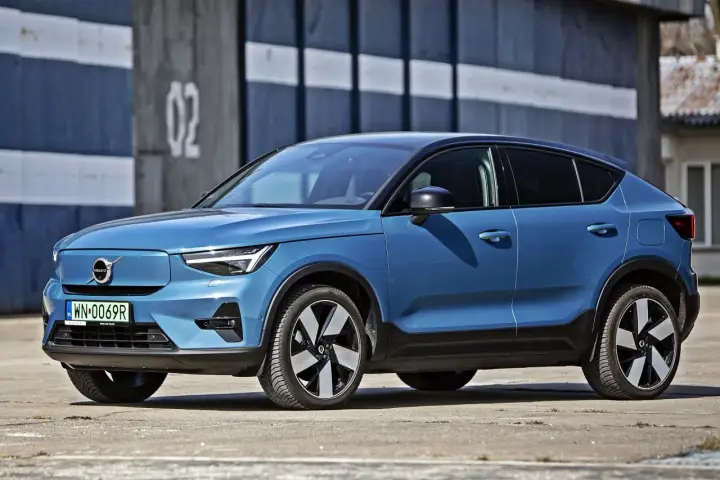 Niebieskie Volvo C40 Recharge, elektryczny SUV, parkuje przed budynkiem z numerem 02.